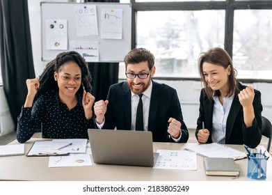 Cheerful Creative Business Partners Working Together In The Office. Multiracial Colleagues Sitting In Modern Office, Using Laptop, They Are Happy Get Good Deal, Big Profit. The Concept Of Win