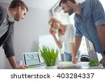 Cheerful creative team using notebook for work