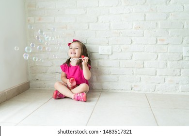 Cheerful cute little kid enjoying while making soap bubbles in living room at home - Powered by Shutterstock