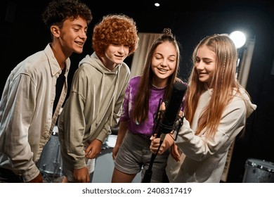 cheerful cute teenagers in everyday vibrant attires singing together into microphone, musical group - Powered by Shutterstock