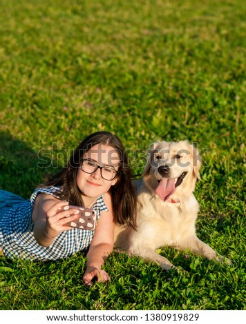 Cheerful cute young woman taking selfie with golden retriever dog on green meadow. beautiful girl and her dog make self-portrait themselves by phone