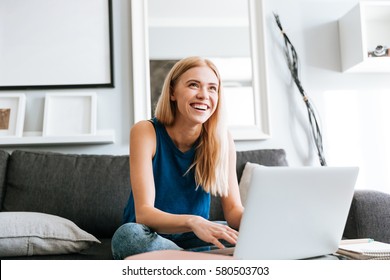 Cheerful Cute Young Woman Using Laptop And Laughing At Home