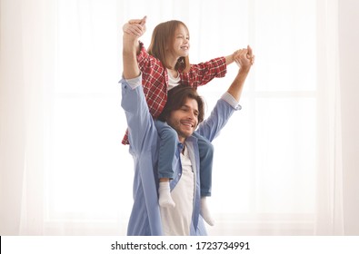 Cheerful dad holding his happy little girl on shoulders, carrying her hands over white background, copy space - Shutterstock ID 1723734991