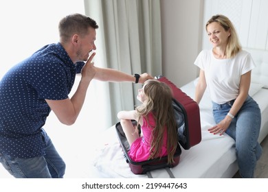 Cheerful Dad And Mom Play Hide And Seek With Child And Suitcase