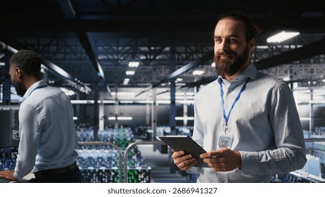 Cheerful data center admin doing maintenance tasks on tablet, ensuring optimal performance. Upbeat IT professional reviewing diagnostics and applying patches to server hub gear,