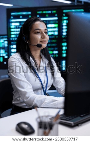 Cheerful data center operator supporting engineering team doing equipment maintenance, talking in headset microphone. Smiling person in server room coordinating technicians using mic