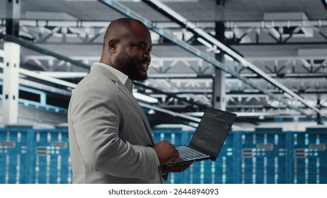 Cheerful data center system administrator reviews code for automation scripts. Jolly server room employee running diagnostics on equipment, doing predictive error detection, camera B