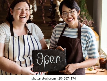 Cheerful deli shop owners showing an open sign - Powered by Shutterstock