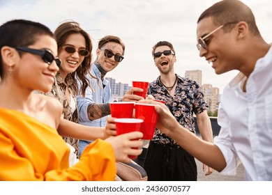 cheerful diverse friends with sunglasses having fun at rooftop party holding red cups with drinks - Powered by Shutterstock