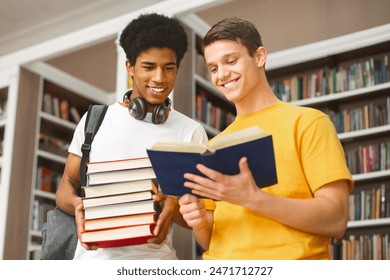 Cheerful diverse teenage friends discussing book in library, free space - Powered by Shutterstock