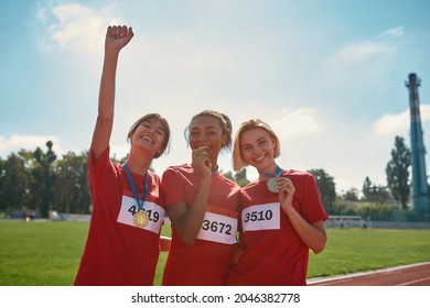 Cheerful Diverse Young Female Athletes With Gold Medals Standing Together On Race Track. Sports, Active Lifestyle, Motivation Concept