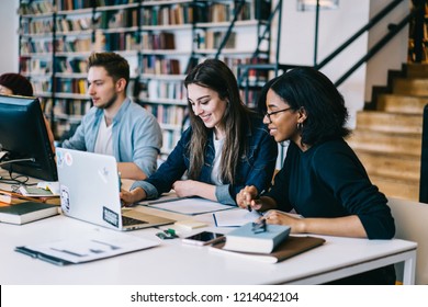 Cheerful diversity group of students sitting in university campus with books and technology learning for exams, multiracial hipster girls smiling and talking while making online research on netbook - Shutterstock ID 1214042104