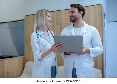 Cheerful Doctor And His Female Colleague Communicating In Reception Area