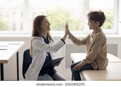 Cheerful doctor and patient kid giving high five in clinic office, laughing after successful examination. Happy pediatrician clapping greeting hands with healthy child, laughing - Powered by Shutterstock