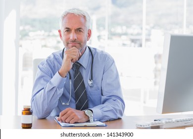 Cheerful Doctor Sitting Behind His Desk At The Office