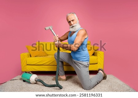 Cheerful elder man showcasing style with humor and vacuuming in a colorful living space