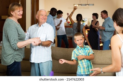 Cheerful Elderly Couple Dancing During Family Holiday Celebration Together With Their Children And Grandkids At Home