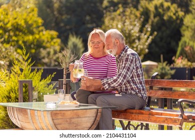 Cheerful elderly couple drinking lemonade and relaxing outdoors, woman pouring a glass of lemonade to her husband - Powered by Shutterstock