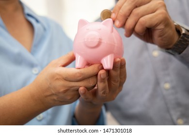 Cheerful elderly couple saving money with putting coin into pigg