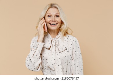 Cheerful Elderly Gray-haired Blonde Woman Lady 40s Years Old Wears Pink Dress Talk Speak On Mobile Cell Phone Conducting Pleasant Conversation Isolated On Plain Pastel Beige Background Studio Portrait