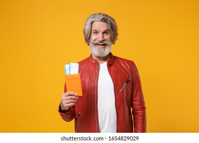 Cheerful elderly gray-haired mustache bearded man in red leather jacket posing isolated on yellow orange background. People lifestyle concept. Mock up copy space. Hold passport tickets boarding pass - Shutterstock ID 1654829029