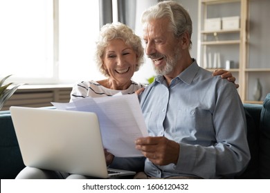 Cheerful elderly grey haired wife and husband sit on couch using computer on-line application banking website check savings feels satisfied, 60s couple examining check utility bills documents concept - Powered by Shutterstock