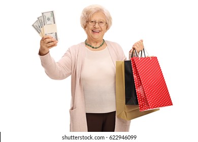 Cheerful Elderly Woman Holding Stacks Of Money And Shopping Bags Isolated On White Background