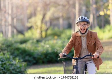 Cheerful Elderly Woman Riding Bicycle In Public Park. Activities For Older People