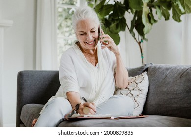 Cheerful Elderly Woman Talking On A Phone On A Couch