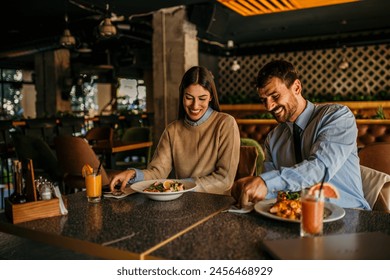 Cheerful elegant couple eating together and having fun in a restaurant - Powered by Shutterstock