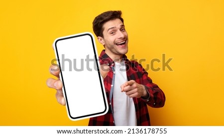 Cheerful Emotional Man Holding Big Blank Cell Phone In Hand Showing White Screen To Camera Pointing At You, Happy Millennial Guy Recommending New Application Or Mobile Website, Mockup Banner Collage
