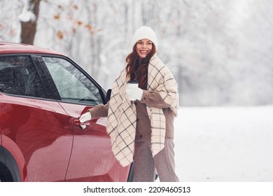 Cheerful emotions. Beautiful young woman is outdoors near her red automobile at winter time. - Powered by Shutterstock