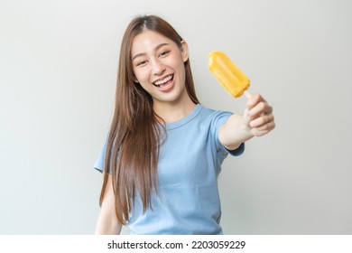 Cheerful Enjoy, Happy Cute Asian Woman Wearing Casual With Brunette Hair, Eating Popsicle, Teenage Girl Holding Ice Pop, Lolly Frozen Stick With Mango Yellow, Passion Fruit Ice Cream Tasty In Summer.