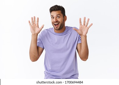 Cheerful Enthusiastic Modern Guy In Purple T-shirt Have Nothing Hide, Raising Hands In Surrender Or Retreatment, Smiling Joyfully, Waving Hands In Hi, Friendly Greeting Gesture, White Background