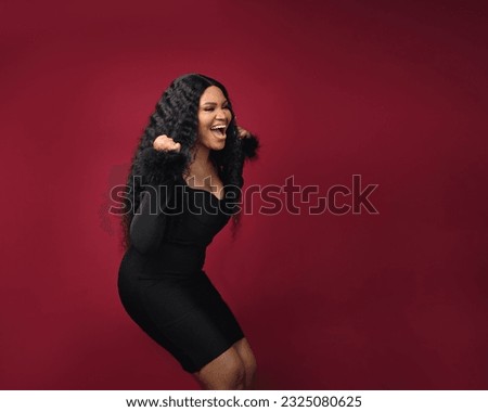 A cheerful excited African woman is excited to win a raffle draw product or empty copy space standing over isolated red background. Model young girl laughing promotion. Advertisement presenting once