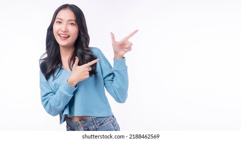 Cheerful excited asian woman use finger pointing to side with product or empty copy space standing over isolated white background. Model young girl laughing promotion. Advertisement presenting concept - Shutterstock ID 2188462569