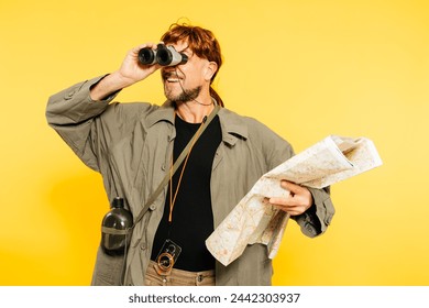 A cheerful explorer in a jacket is looking through binoculars and holding a map, ready for adventure against a vivid yellow backdrop.