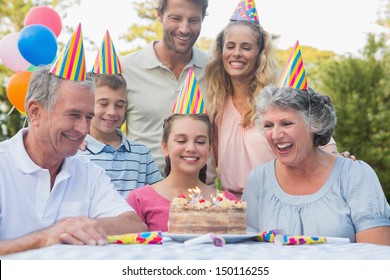 Cheerful Extended Family Celebrating A Birthday Outside At Picnic Table