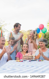 Cheerful Extended Family Clapping For Little Girls Birthday Outside At Picnic Table