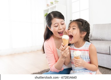 Cheerful Family Of Beautiful Mother With Cute Daughter Eating Ice Cream At Home And Playing Fun Together In Living Room.