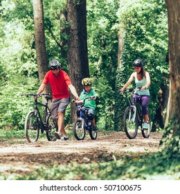 Cheerful Family Biking Together In Park