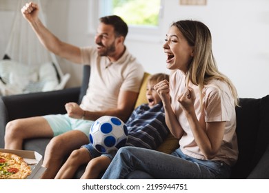 Cheerful family celebrating the victory of their soccer team at home - Powered by Shutterstock