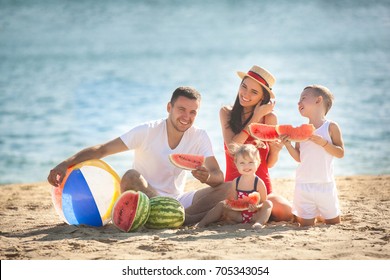 Cheerful family eating watermelon on the beach. Little kids and their parents on the sea shore having fun. Joyful family on the seaside - Powered by Shutterstock