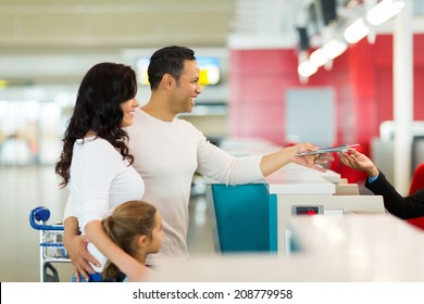 Cheerful Family Handing Over Air Ticket At Airport At Check In Counter