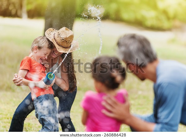 cheerful\
family having fun she does a water gun fight, mom and son against\
dad and daughter, focus on mom and her\
son