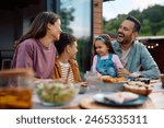 Cheerful family having fun while communicating during a meal on their terrace. 