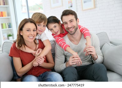 Cheerful Family At Home Sitting In Sofa