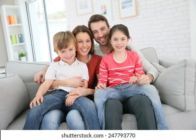 Cheerful Family At Home Sitting In Sofa