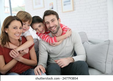 Cheerful family at home sitting in sofa