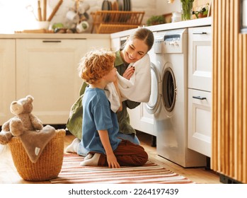 Cheerful   family: kid son helping mother at linen in basket while doing laundry near washing machine in flight kitchen in weekend at home   - Powered by Shutterstock